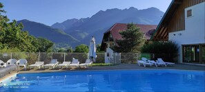 Une piscine avec des chaises longues et une vue sur les montagnes en arrière-plan.