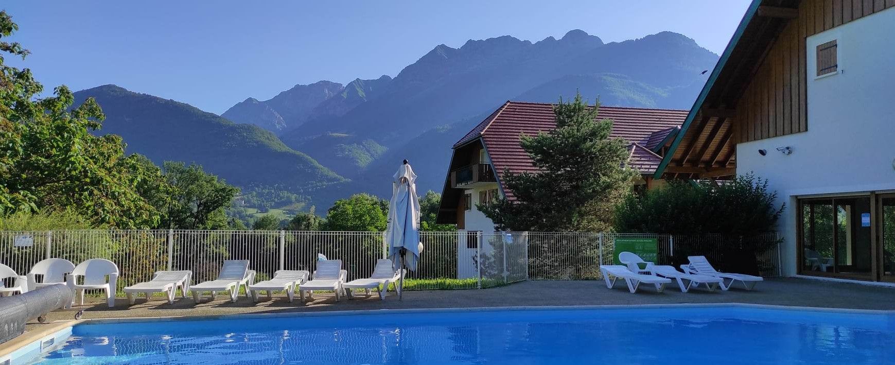 Une piscine avec des chaises longues et une vue sur les montagnes en arrière-plan.