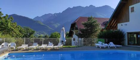 A swimming pool with lounge chairs and a mountain backdrop.