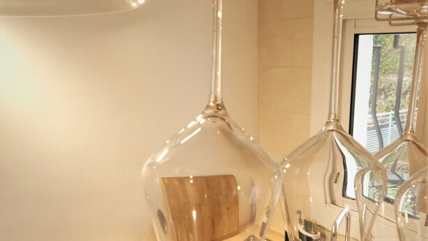 Une cuisine dotée d’un plan de travail en bois, d’un évier en acier inoxydable et d’une carafe à vin en verre.