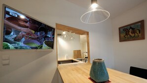 Une cuisine moderne avec un plan de travail en bois, un vase turquoise et un téléviseur qui affiche des images d’aliments.