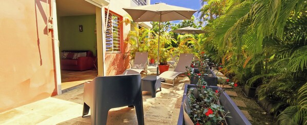 An outdoor seating area with chairs and tables, surrounded by potted plants and palm trees. - T2 D'ALICE CLASS 2* 1.2 KM FROM PLAGE DU BOURG (SAINTE ANNE)