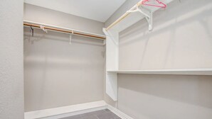 A walk-in closet with a wooden rod and a white shelf.