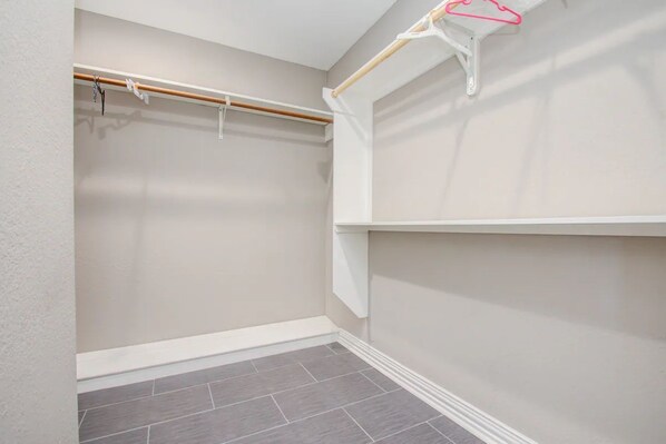 A walk-in closet with a wooden rod and a white shelf.