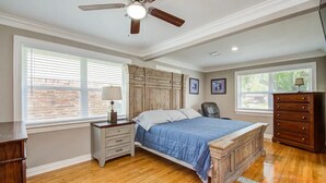 A bedroom with a wooden bed, a nightstand, a dresser, and a ceiling fan.