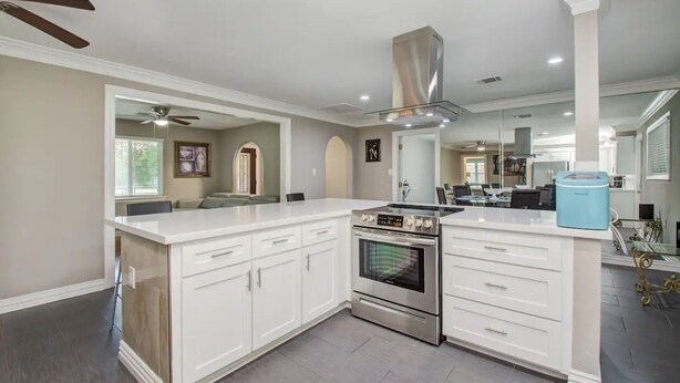 A modern kitchen with white cabinetry, a stainless steel range, and a built-in oven.