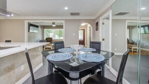 A modern dining area with a glass table, black chairs, and a white counter.