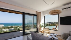 Un salon moderne doté d’une grande fenêtre donnant sur une piscine et la mer.