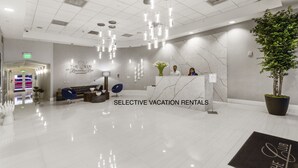 A modern reception area with a marble reception desk, a large potted plant, and a blue chair.
