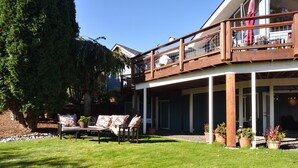 Uma casa de dois andares com alpendre, área de estar externa e vasos de plantas.