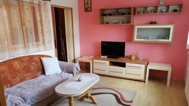 Ein Wohnzimmer mit einer Couch, einem Couchtisch, einem Fernseher und Regalen mit Dekoration.