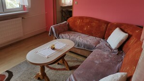 Ein Wohnzimmer mit einer Couch, einem kleinen Tisch, einer Heizung und einem Fenster mit Vorhängen.