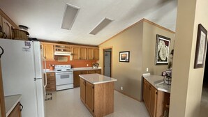 Una cocina compacta con armarios de madera, un refrigerador blanco, una estufa y una pequeña isla.