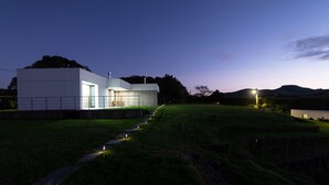 A modern building with a flat roof and large windows, surrounded by a grassy area and a stone wall. - Vila Vicente-Wellness, Fantastic Views and Parking (S. Vicente Ferreira)