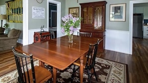 A dining room with a wooden table, four chairs, a vase with flowers, a wooden cabinet, and a framed picture on the wall. - 1880 Farmhouse With Direct Access to Tall Pines ATV Park (Andover)