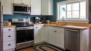 A kitchen with white cabinets, stainless steel appliances, a window with a view, and a wooden countertop. - 1880 Farmhouse With Direct Access to Tall Pines ATV Park (Andover)