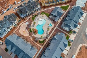 An aerial view of a residential area with modern houses, a central swimming pool, and a landscaped park area. - O-65| Poolhouse at Ocotillo Springs * Private Pool (Santa Clara)