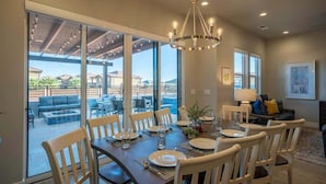 A dining area with a large table set for six, surrounded by chairs, with a view of the outdoors through large sliding glass doors. - O-65| Poolhouse at Ocotillo Springs * Private Pool (Santa Clara)