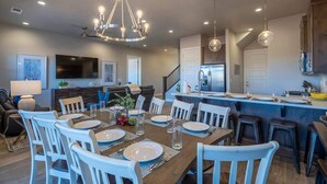 A modern kitchen with a central island, a dining area with white chairs, and a chandelier. - O-65| Poolhouse at Ocotillo Springs * Private Pool (Santa Clara)