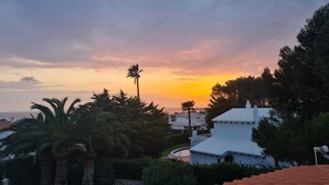 Ein Wohngebiet mit weißen Gebäuden, Palmen und einem Sonnenuntergang.