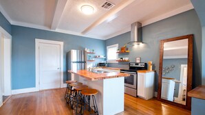 Una cocina moderna con una isla central, taburetes de bar, refrigerador, microondas, horno y un espejo grande.