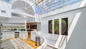 A modern interior with a kitchen, dining area, and a large window. - 6th St Mansion w Indoor Pool + Walk to Everything (Austin)