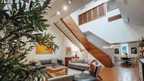 A spacious living area with a staircase, a dining table, and a kitchen area. - 6th St Mansion w Indoor Pool + Walk to Everything (Austin)