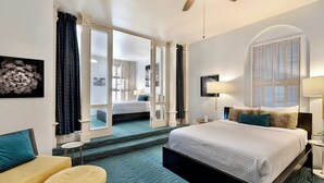 Ein Hotelzimmer mit einem großen Bett, einer Couch, einem kleinen Tisch und einem Deckenventilator.