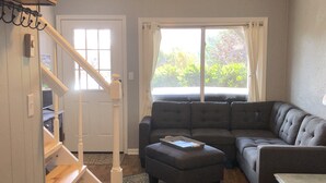 A living room with a sectional sofa, a small ottoman, a table, and a staircase. - Big Views, Hot Tub, Dog Friendly, 5min to BR (Blowing Rock)