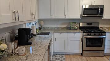 A modern kitchen with white cabinets, a stainless steel microwave, an oven, and a granite countertop.