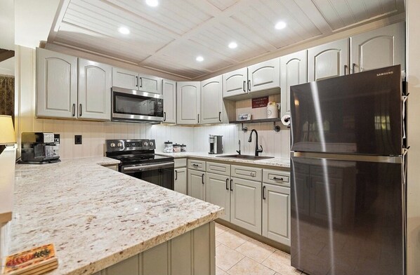 Modern kitchen with stainless steel appliances, light-colored cabinetry, and a granite countertop.
