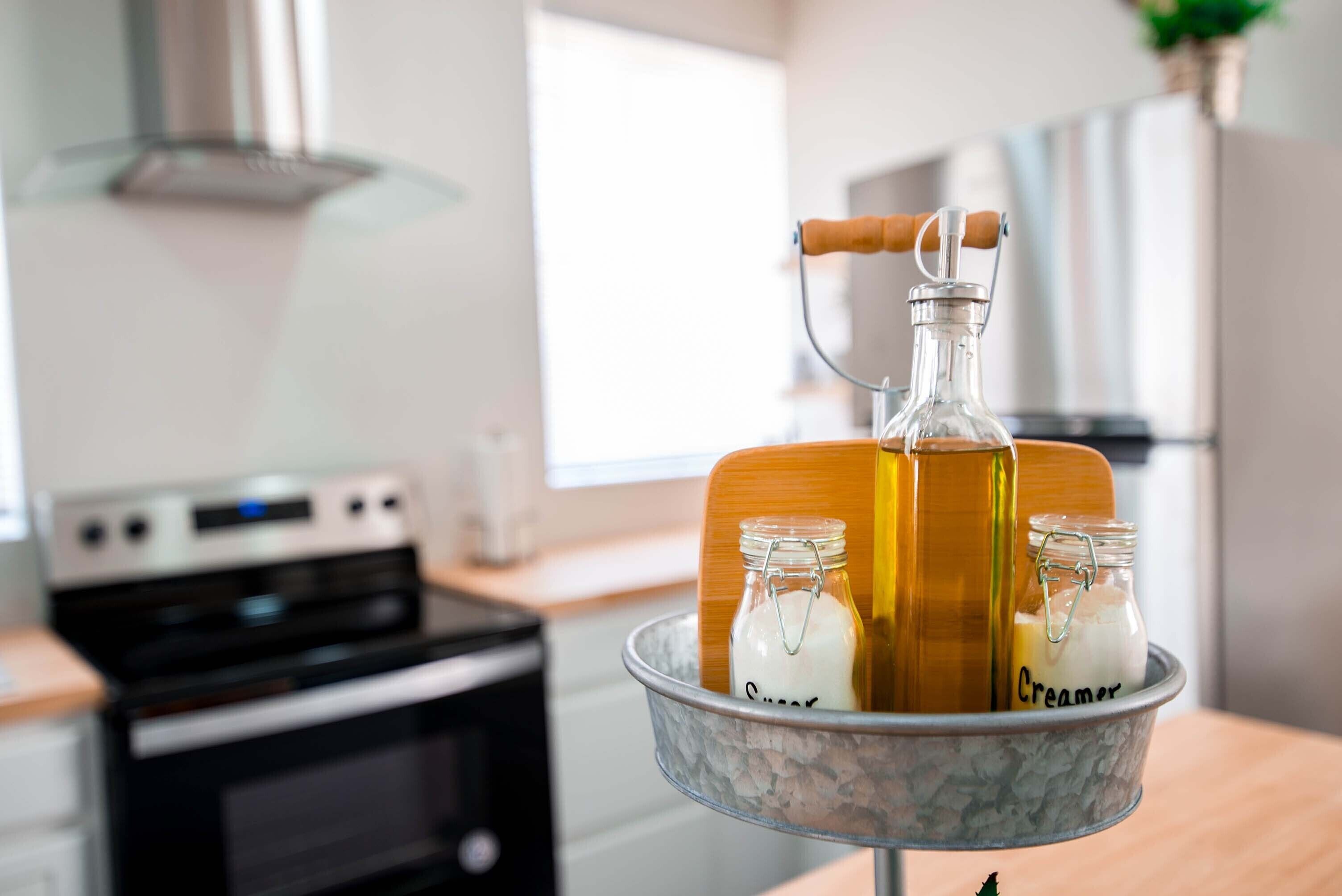 Una cocina con estufa, tabla de cortar de madera y dos frascos de vidrio etiquetados como 'Creamer' y 'Sugar'.