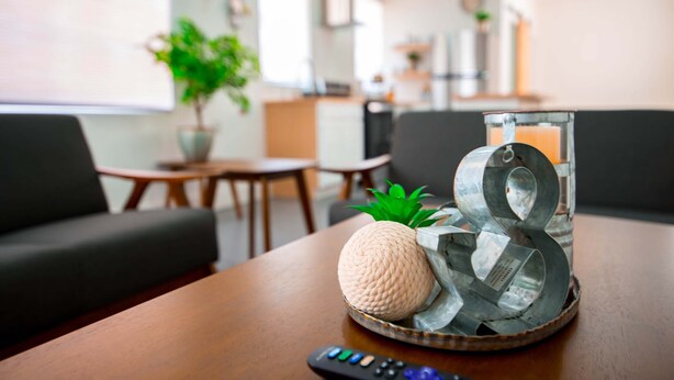 A wooden table with a remote control, a pineapple, and a decorative glass vase with metal elements. - Quaint cozy studio located in the heart of El Paso  (El Paso)