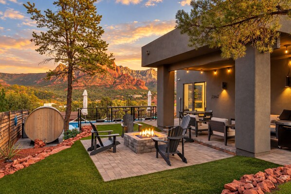 A modern outdoor patio with a fire pit, seating, and a view of mountains.