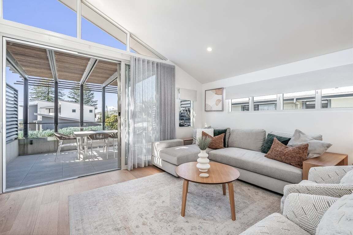 A modern living room with a sofa, a coffee table, and a dining area with chairs.