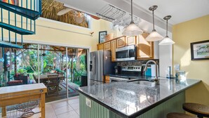 A kitchen with a large island, stainless steel appliances, and a view of a lush garden. - Tiki Hut in tropical paradise (Dunedin)