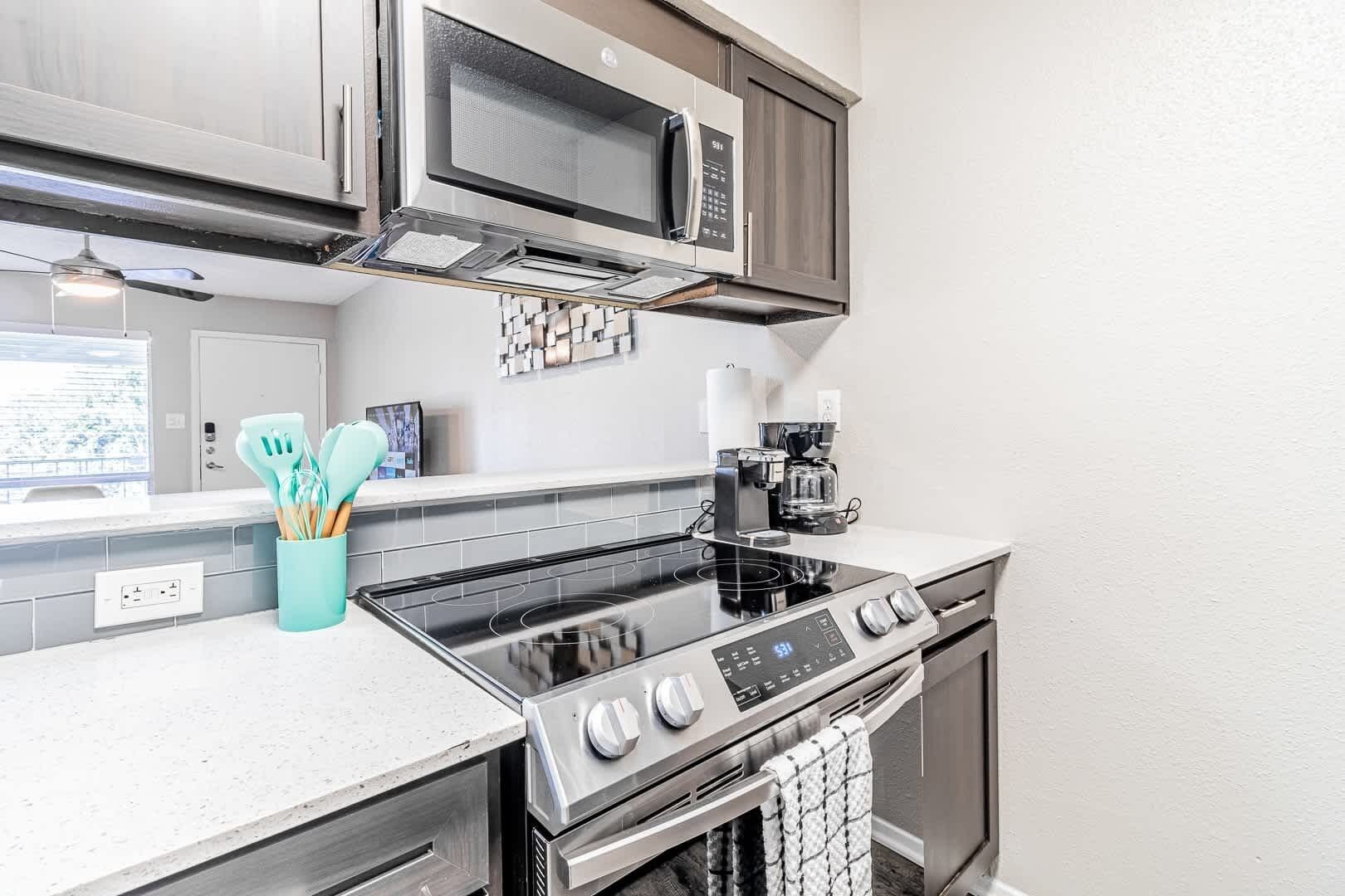 A modern kitchen with a built-in microwave, stove, and coffee maker.