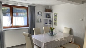 A dining area with a table covered by a white tablecloth, surrounded by four chairs and two benches. - Casa Siepelunga (Villmar)