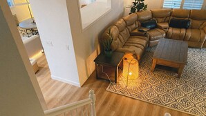 A spacious living room with a leather sofa, a patterned rug, and a small table with a lantern. - Golf course house with 2 master bedrooms (Fontana)