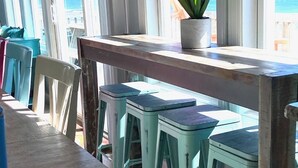 A bar area with a wooden counter, three stools, and a potted plant. - Oceanfront Oasis House 5 bedroom, 3.5 bath Elevator - Excellent Reviews (Holly Ridge)