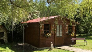 A wooden cabin with a red roof, a porch, and a swing. - Pleasures and Idleness... (Boisredon)