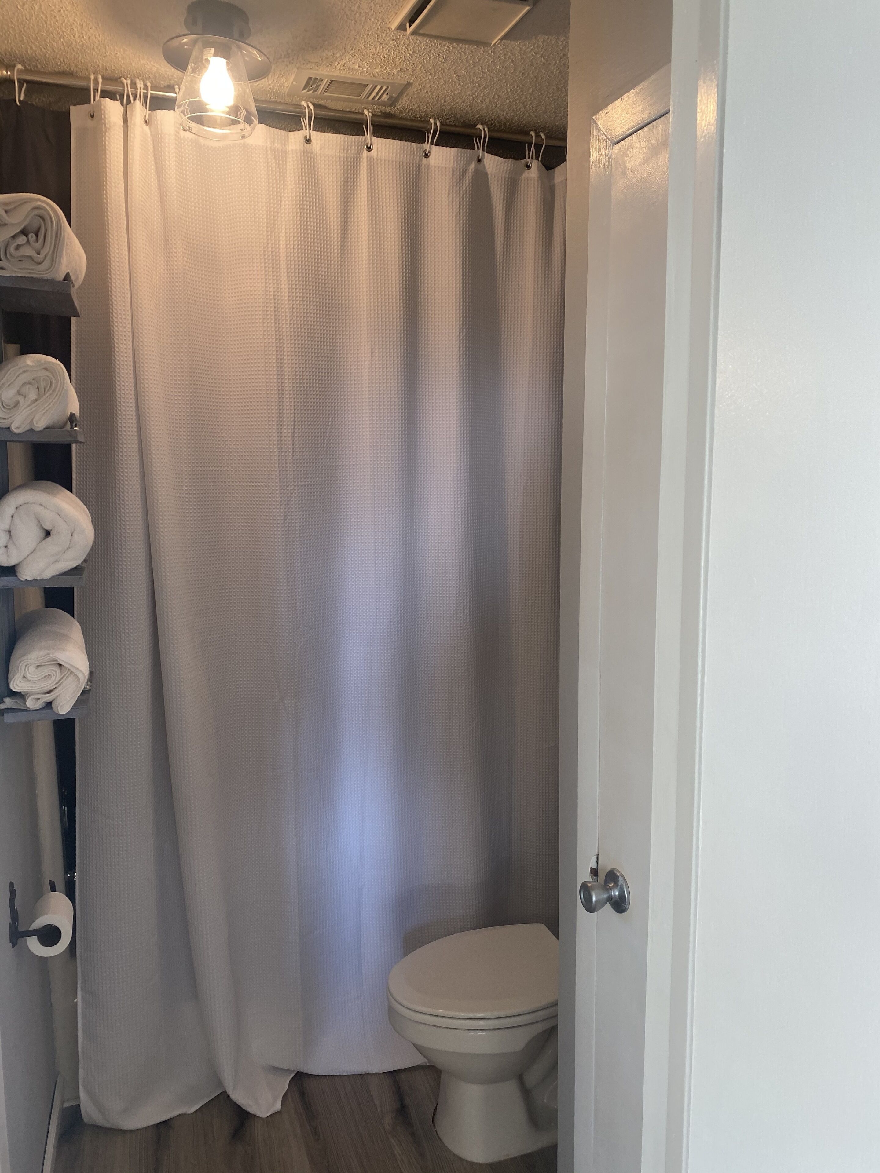 Une salle de bain équipée de toilettes, d’un rideau de douche et d’un porte-serviettes avec des serviettes.