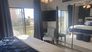 A bedroom with a large bed, a chair, and a view of a balcony. - Private condo next to state park and pier-now booking for summer! (Gulf Shores)