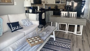 A compact living space with a kitchenette, a dining area, and a sofa with decorative pillows. - Private condo next to state park and pier-now booking for summer! (Gulf Shores)