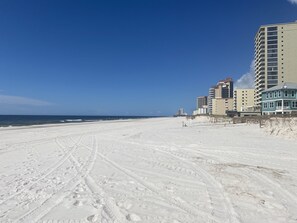 A beach with footprints leading to a building with multiple floors and balconies. - Private condo next to state park and pier-now booking for summer! (Gulf Shores)
