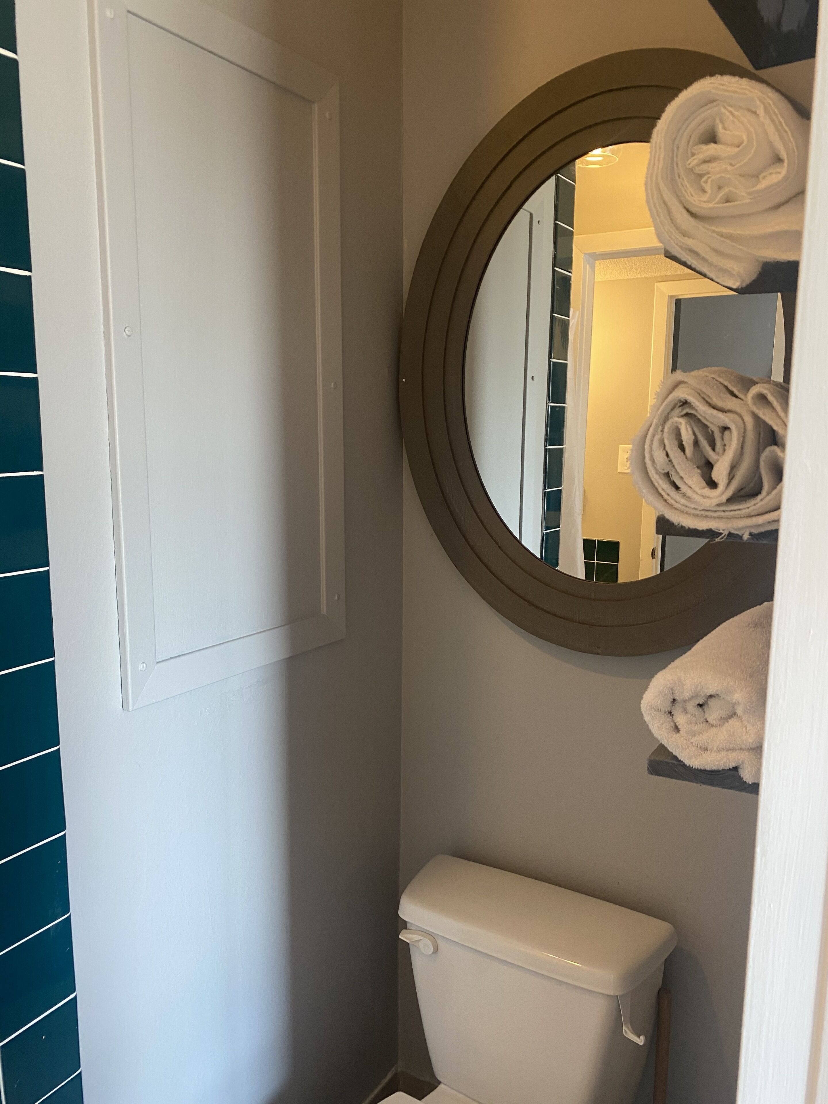 Une salle de bain équipée de toilettes, d’un miroir et d’un porte-serviettes.