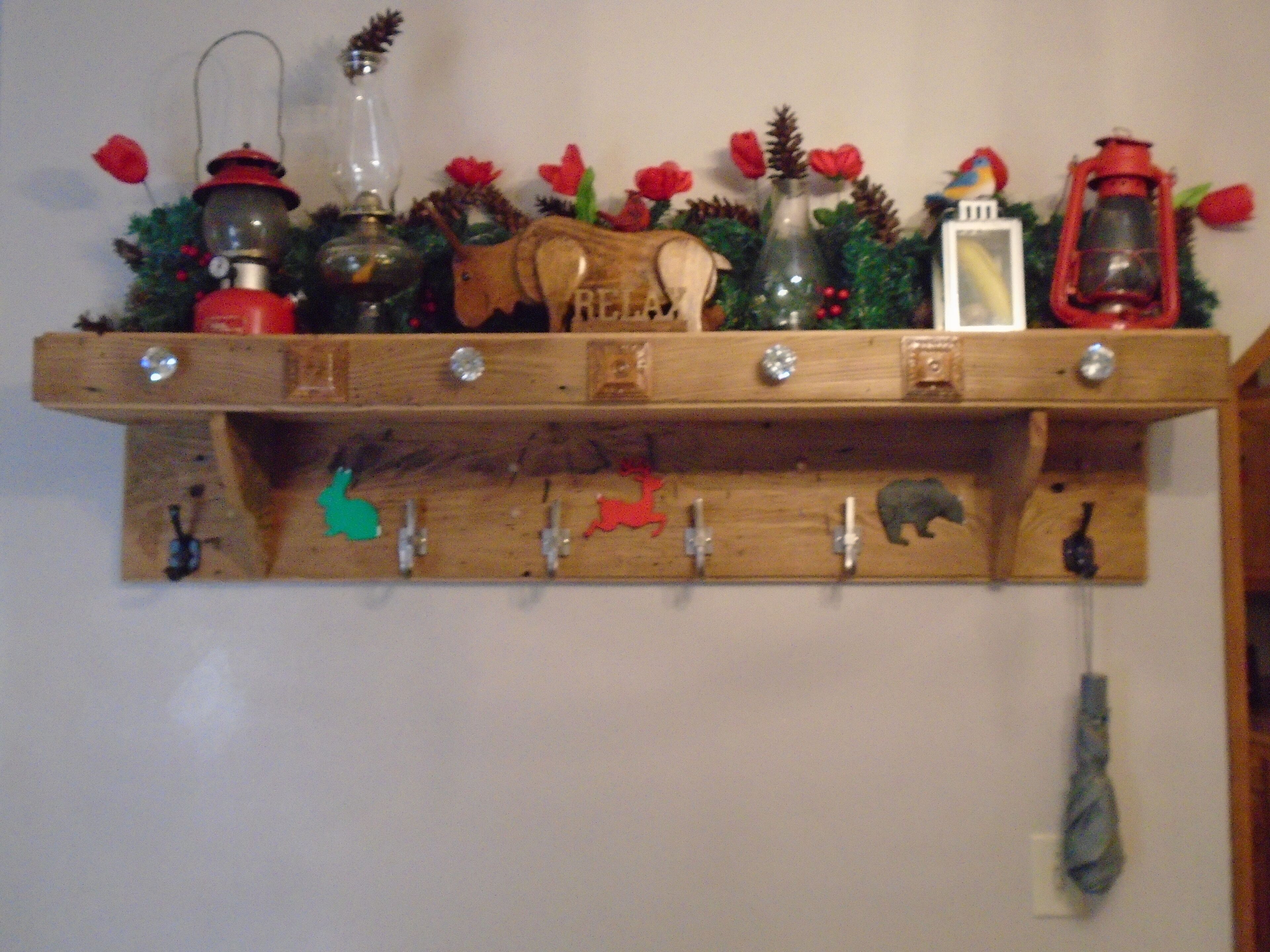 A wooden wall-mounted shelf with various decorative items including lanterns, a wooden horse, and animal-shaped hooks.