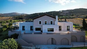 A modern house with a flat roof, multiple windows, and a balcony. - Luxurious Panoramic View Villa (Archanes-Asterousia)