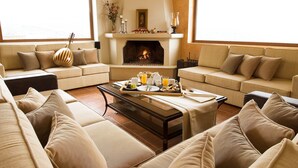A cozy living room with a fireplace, sofas, and a breakfast tray. - Luxurious Panoramic View Villa (Archanes-Asterousia)