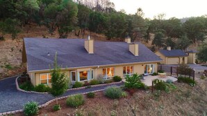 Une maison à deux étages avec un toit en pente, de grandes fenêtres et un espace patio.